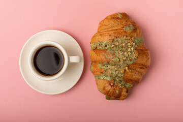 Aromatic coffee in a cup with pistachio croissant on a textural background.Espresso. Morning drink. Breakfast. Cheerful morning concept. Place for text. Place to copy.