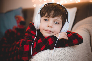 A boy with headphones is lying on the sofa lifestyle. The boy listens to music.
