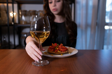 Young woman sitting in the kitchen with a glass of wine. Teen alcoholism concept, alcohol addiction problems among women