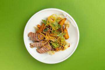 Salad with pieces of duck in a plate on a green background.