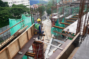 MELAKA, MALAYSIA - JUNE 5, 2022: Construction workers work at height and wear safety gear to ensure their safety. They work in groups and carry out their specific tasks.