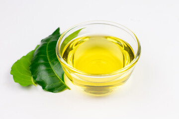 Neem oil in transparent bowl with neem leaf isolated on white background.