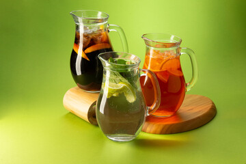 Cocktails and lemonades in decanters on a green background.