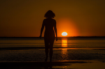 The girl runs on the water at sunset. Bather. Rest on the sea