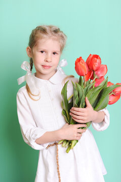Portrait Of Cute Girl Holding Yellow Flowers Against Blue Background