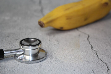 Ripe yellow banana and stethoscope. Isolated on a rustic gray background. Selective focus....