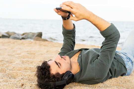 Hispanic man using smartphone on beach