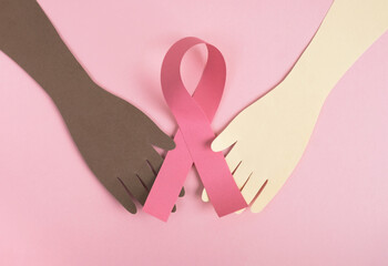 Breast cancer awareness concept. Womans hands various skin tones holding pink ribbon on pastel...