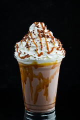 Caramel milkshake in a plastic cup. on a black background. Free space for text.