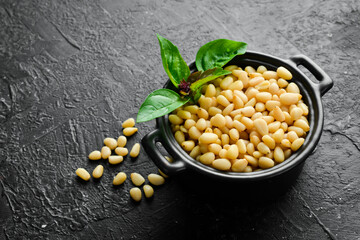 Pine nuts in a black stone bowl. On a concrete background.