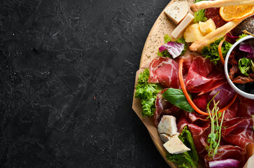 Antipasto Assortment of appetizers: cheese, prosciutto, salami, bacon, olives and capers on a...