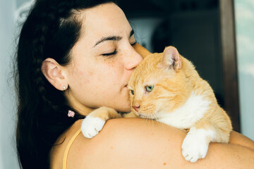 brunette gril give a kiss to an orange cat