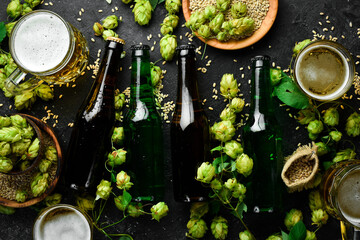 Fresh beer in bottles and glasses on a black stone background. Banner.