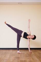 Naklejka premium Young pretty yoga girl portrait, doing yoga poses indoors. Beautiful brunette short-haired woman doing pilates exercises. Woman in sports suit meditating. Woman stretching alone, flexible and slim.