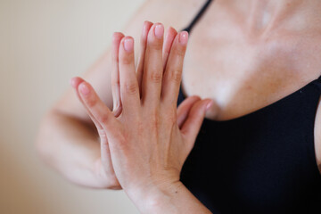 Closeup of woman hands in yoga pose. Woman hands doing pilates exercises. Beautiful palm with pink manicure. Flexible girl doing yoga poses indoors	