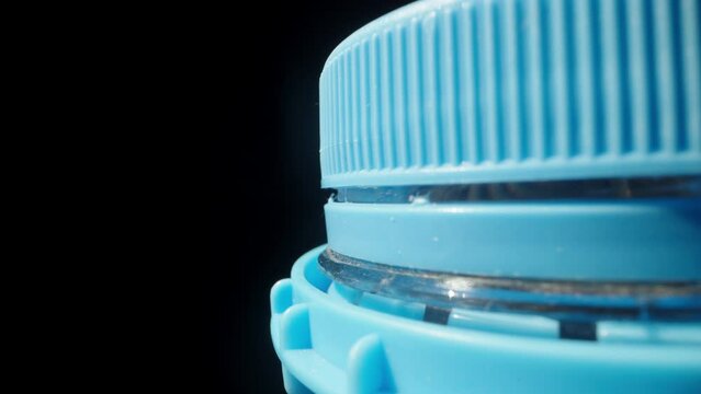 I unscrew the big blue cap from the water bottle. Dolly slider extreme close-up.