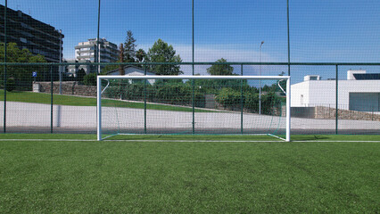 Sports field in a residential area with artificial green grass and football goal at Santo Tirso Municipal Sports Complex in Portugal.
