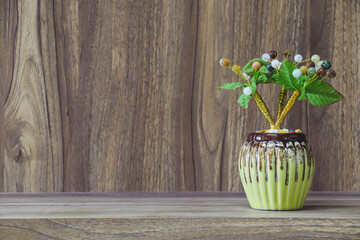 Fake flowers in a vase placed on a table on a wooden table with copy space for design wood grain vintage background.