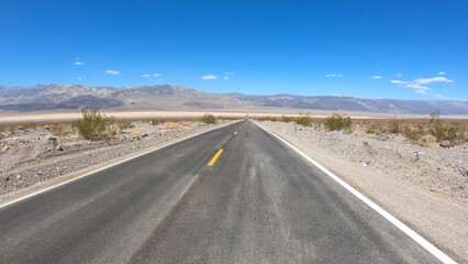 State Route 190 crossing Panamint Valley in Death Valley National Park, California, United States. Empty desert road in Death Valley with clear blue sky.