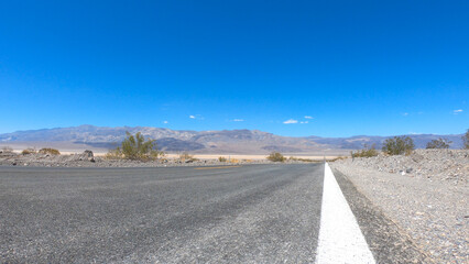 State Route 190 crossing Panamint Valley in Death Valley National Park, California, United States. Empty desert road in Death Valley with clear blue sky.