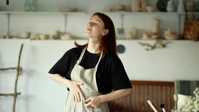 Girl potter wipes her hands on her apron and poses