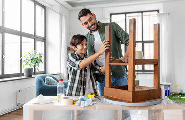 furniture renovation, diy and home improvement concept - father and son sanding old round wooden...