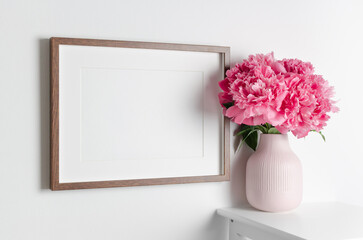 Landscape artwork frame mockup on white wall with fresh flowers