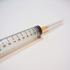 Syringe on a white background with orange ink.