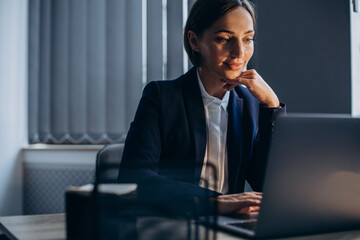 Business woman working in an office on laptop till late