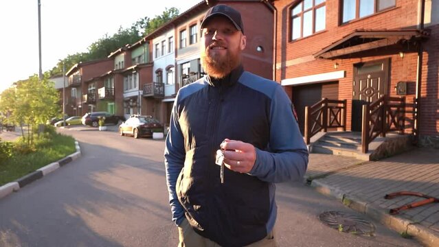 Happy middle aged man with red beard In Front of New Home with Keys