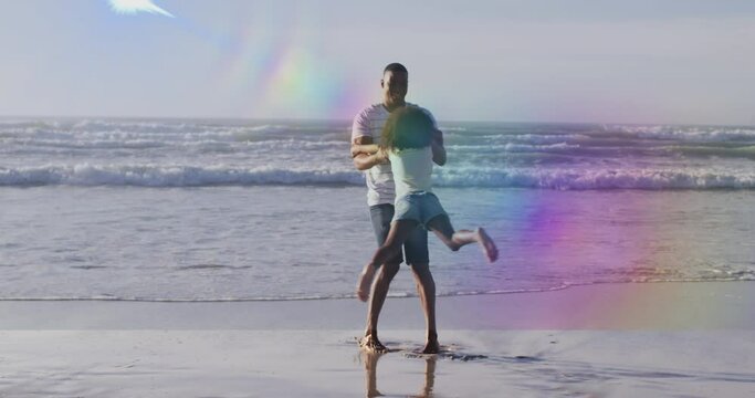 Animation of light spots over african american father with daughter at beach