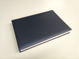 Book, notebook, no inscription, thick and closed, with a gray-blue padded cover, on a white background