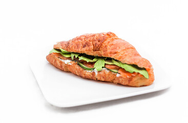 Croissant with salmon, lettuce and fresh cucumber slices.