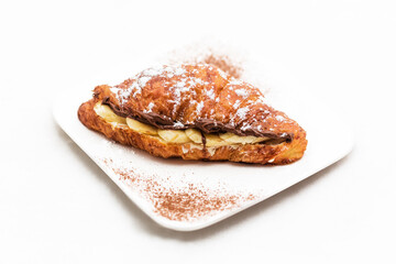 Croissant with chocolate butter and banana isolated on a white background. Horizontal photo