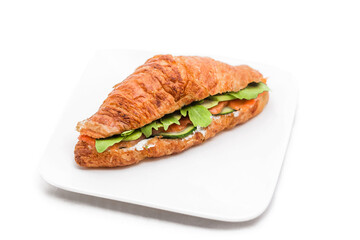 Croissant with salmon, lettuce and fresh cucumber slices.