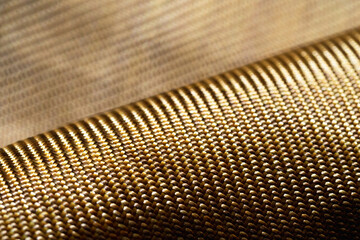 Roll of bulletproof material aramid. Shining aramid kevlar background. Bronze kevlar texture and...