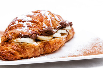 Croissant with chocolate butter and banana isolated on a white background.