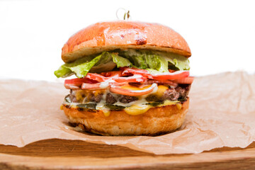 Craft beef burger on wooden plate isolated on white background.