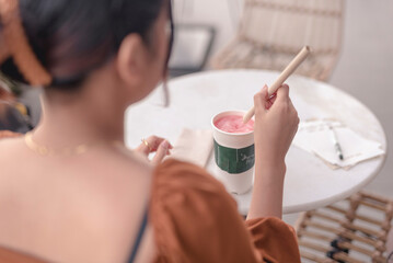 Obraz na płótnie Canvas A young woman places the paper straw inside the watermelon shake and stirs the drink.