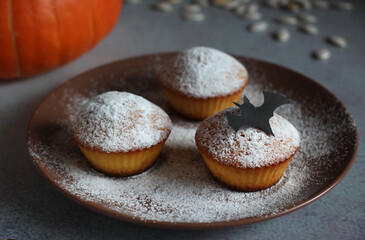 powdered muffins with pumpkin, pumpkin seeds and black bat