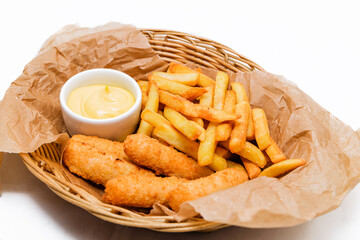 Fototapeta na wymiar Breaded cheddar cheese sticks with french fries and sauce. Served in a wicker basket on craft paper.