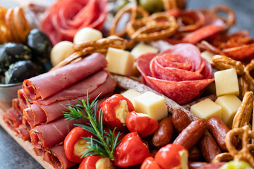 Cutting board with ham, salami, cheese, cracker and olives on a wooden board.