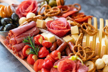 Cutting board with ham, salami, cheese, cracker and olives on a wooden board.