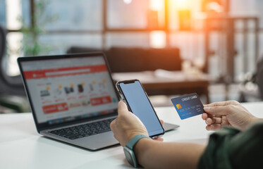 Online shopping concept, young man hands holding mobile smart phone showing payment success on screen and credit card with laptop on table while sitting in office, lifestyles technology