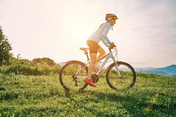 Cyclist Woman riding bike in helmets go in sports outdoors on sunny day a mountain in the forest. Silhouette female at sunset. Fresh air. Health care, authenticity, sense of balance and calmness.