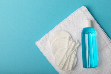 Micellar water and cotton pads for removing make-up. Cleansing the skin of sebum and makeup. Composition on a blue background. Beauty concept. Copy space text. flat lay