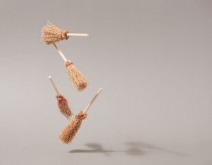 Halloween witch brooms floating against beige background. Witchcraft conceptual backdrop