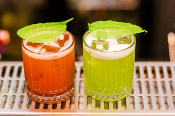 view on glass with red and green drink on bar. Blurred background