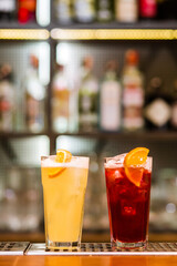 view on glass with red and yellow drink on bar. Blurred background. Horizontal photo