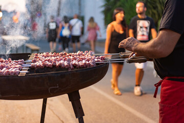man roasting meat skewers on the street during a folk festival in italy